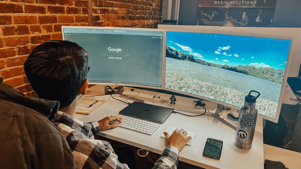 man sitting in front of two computer screens with Google browser open in front of him