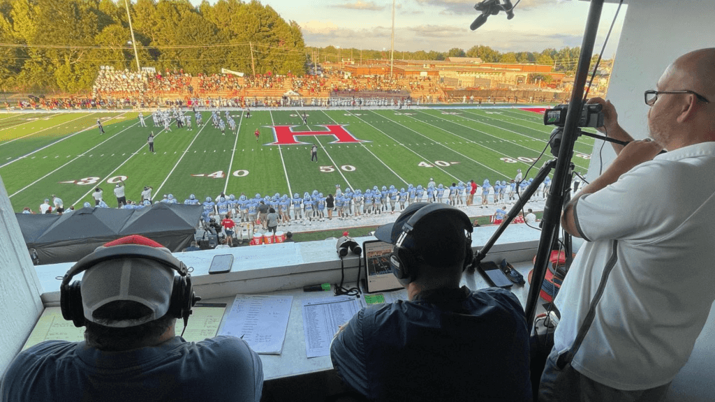 A view from the press box of a football game as a livestream is happening online and men learning to block live stream promoters in the comments